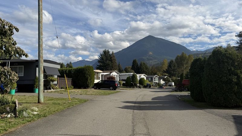 A paved street in the park, lined with homes, with a mountain behind